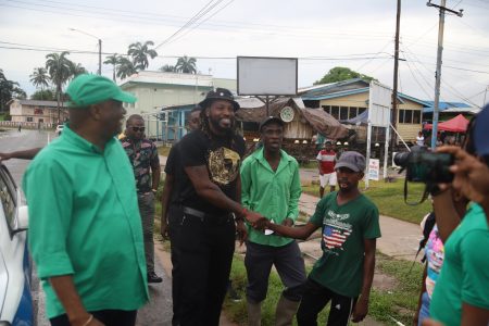 Chris Gayle (centre) greeting fans in Linden on Saturday. At left is Director General of the Ministry of the Presidency, Joseph Harmon. (Terrence Thompson photo)