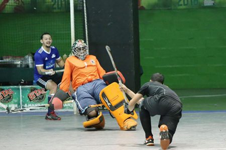 Jason DeSantos of YMCA Old Fort is denied by the advancing Medroy Scotland of Bounty GCC during their Division One clash in the GTT National Indoor Hockey Championships at the Cliff Anderson Sports Hall, Homestretch Avenue