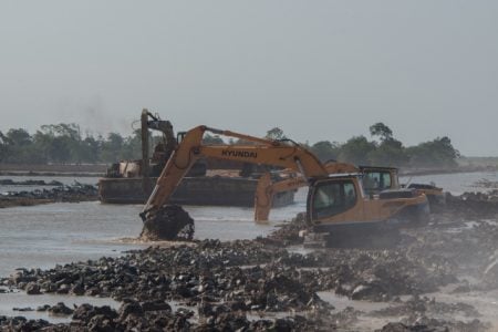 Excavators removing mud from the Bellamy Canal to build a wall behind existing boulders along the foreshore in Mahaicony. (DPI photo)
