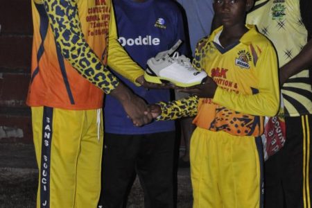 Siddiq Mohamed presents Gladwin Henry Jr., with a pair of boots donated by West Indies cricketer Keemo Paul.