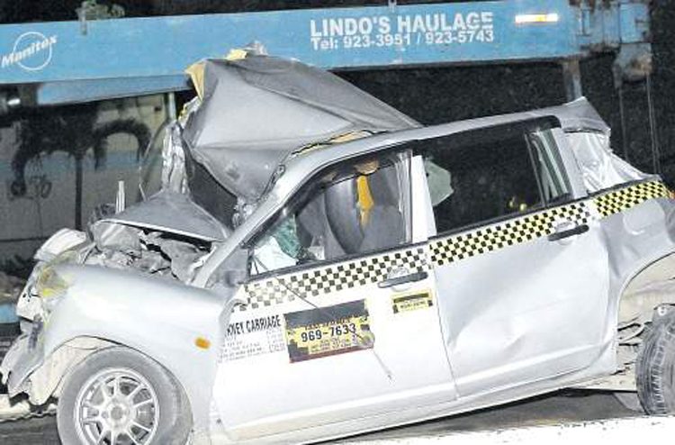 The taxi that was crushed by a garbage truck in the gruesome accident that claimed the life of a seven-year-old student at Clan Carthy Primary School in Kingston yesterday. (Photos: Garfield Robinson)