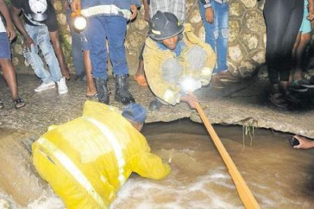 Members of the Jamaica Fire Brigade, assisted by residents, search a gully in August Town, St Andrew, after nine-year-old Kyle Richards was washed away while on his way home during heavy rain on September 25. His body was found on Sunday. (Photo: Garfield Robinson)