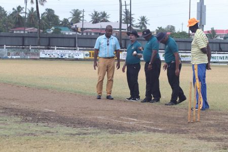 The match referee, Arleigh Rutherford and umpires inspect the damage done by the seven-minute rain (Romario Samaroo photo)