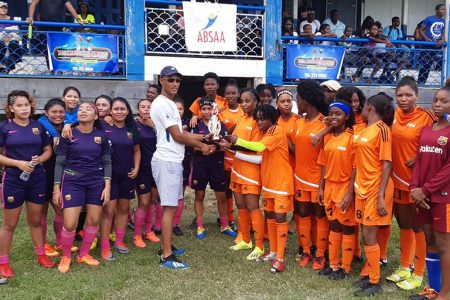 The Fruta Conquerors Ladies collecting their trophy from a tournament representative in the presence of the Lady Panthers after their match at the GFC ground.
