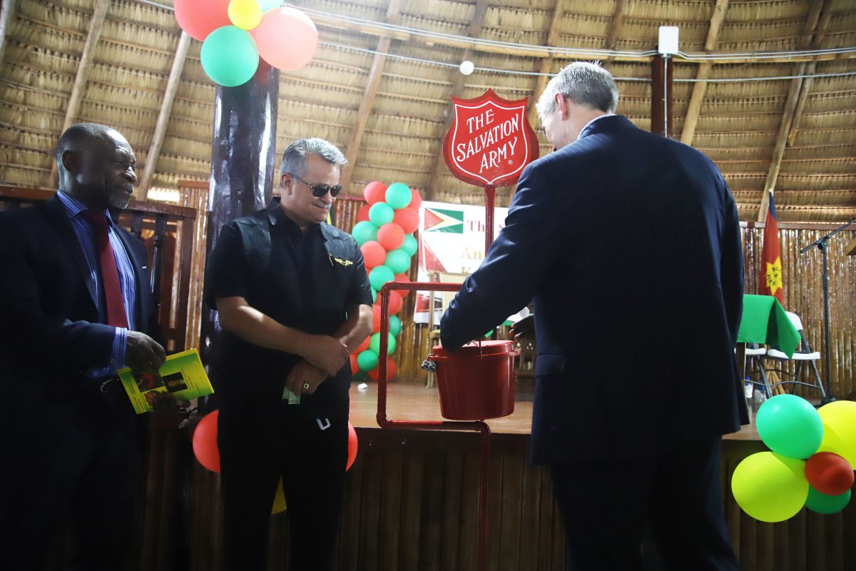 First contribution: Rod Henson, Country Manager of ExxonMobil Guyana making his first contribution during the launch of the Salvation Army Guyana Division annual Christmas kettle appeal as Foreign Secretary of the Ministry of Foreign Affairs Carl Greenidge and Roraima Airways Chief Executive Officer Captain Gerry Gouveia looks on. (Photo by Terrence Thompson) 