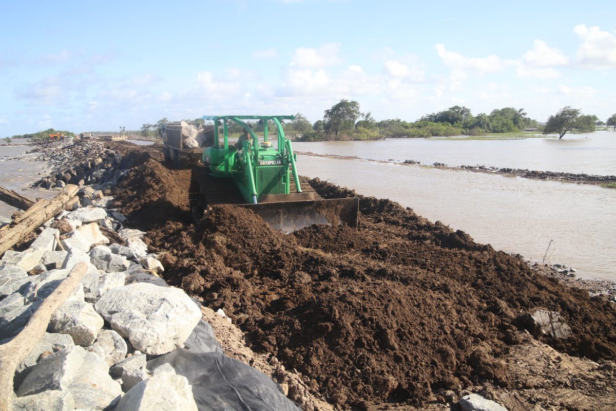 A fbulldozer spreads a truck load of dirt along the manmade earth dam which is being used to construct the sea defence at Mahaicony [Photo by Terrence Thompson)