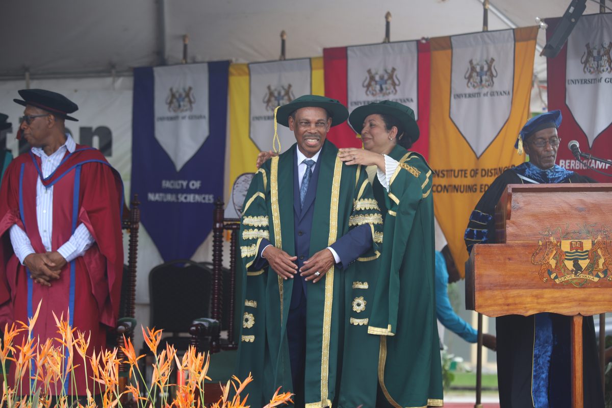 During his installation ceremony Dr. Edward Green is dressed in the robes of Chancellor of the University of Guyana by Professor Paloma Mohamed, Chair of the university’s Transitional Management Committee. (Photo by Terrence Thompson) 
