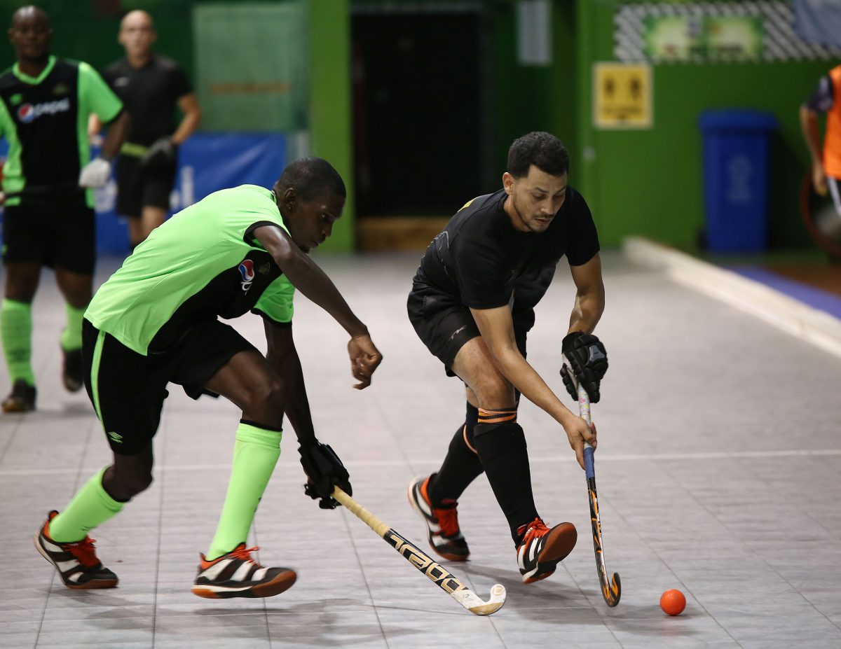 Old Fort’s Jason DeSantos (right) trying to maintain possession while being challenged by Jamarj Assanah of Hikers in the Diamond Mineral Water Indoor Hockey Festival at the Cliff Anderson Sports Hall, Homestretch Avenue.