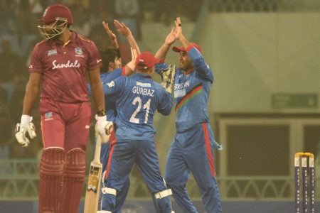  Karim Janat celebrates taking the key wicket of West Indies captain Kieron Pollard with his teammates.