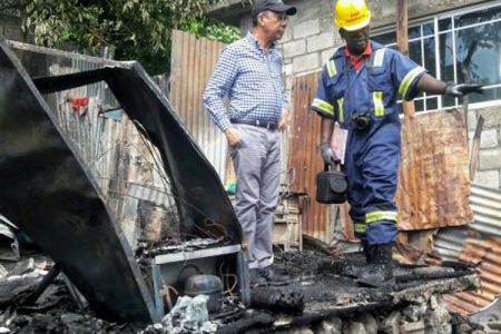 A fire investigator speaks to National Security Minister Dr Horace Chang as he examines the remains of the house in which the two brothers died - Albert Ferguson/Jamaica Gleaner photo.
