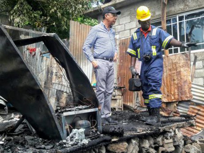 A fire investigator speaks to National Security Minister Dr Horace Chang as he examines the remains of the house in which the two brothers died - Albert Ferguson/Jamaica Gleaner photo.
