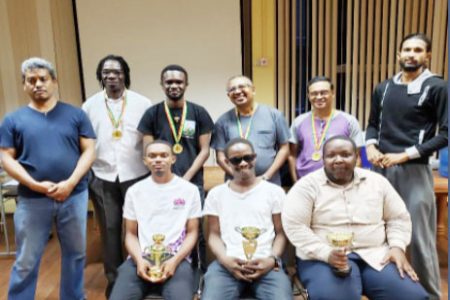 Wendell Meusa (seated at centre) was the winner of the third Gaico Construction chess tournament. On his left is Anthony Drayton (second place) and at right is Ronuel Greenidge (third). Runners-up of the tournament with medals were (from left) Frankie Farley, Davion Mars, Loris Nathoo and Shiv Nandalall. Flanking the group are the arbiters/tournament directors John Lee (left) and Rashad Hussein (right).