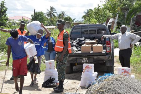 Residents collecting their food hampers and cleaning supplies. Looking on is Minister of Citizenship,  Winston Felix. (Ministry of the Presidency photo)
