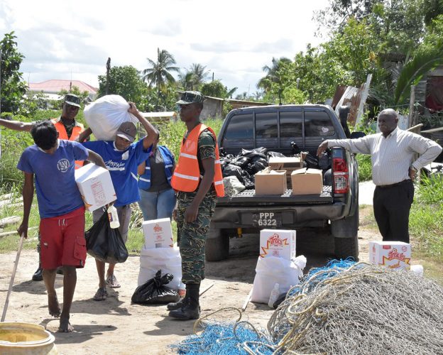 Residents collecting their food hampers and cleaning supplies. Looking on is Minister of Citizenship,  Winston Felix. (Ministry of the Presidency photo)