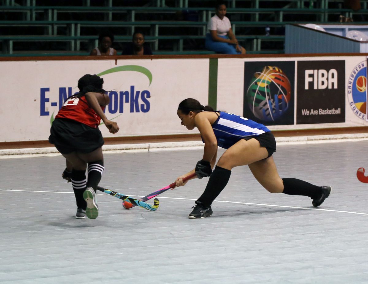 GCC Spartans defender Kirsten Gomes attempting a penalty corner strike against YMCA Old Fort during their matchup in the Sunshine Snacks Junior Hockey Championship at the Cliff Anderson Sports Hall, Homestretch Avenue
