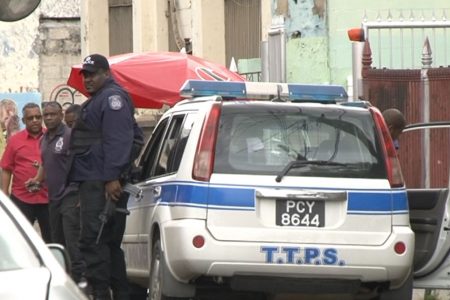Police officers outside the South East Port-of-Spain Secondary School on Nelson Street, yesterday.