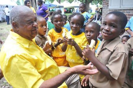 Lenworth Fulton (left), president of the Jamaica Agricultural Society, shares locally grown bananas with Marquis Murray (right) and his classmates from St Benedict's Primary School a the expo on Monday.