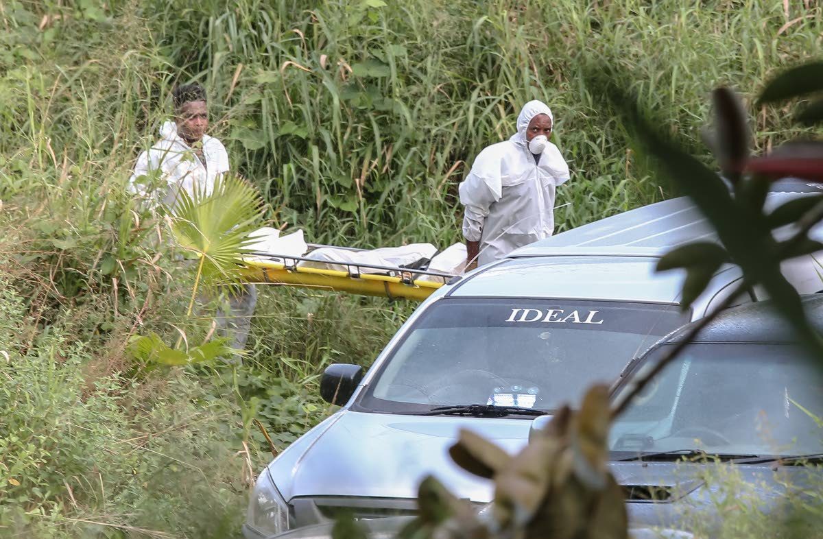 Undertakers from Ideal Funeral Sanctuary Ltd remove the body of an unidentified woman from a lot of land owned by HCL along Caura Royal Road, Caura. – Jeff Mayers