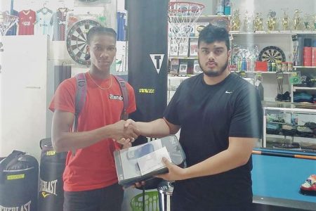 Shemar Halley (left) receives his sponsorship from Proprietor of West Indian Sports Complex, Javed Khan.