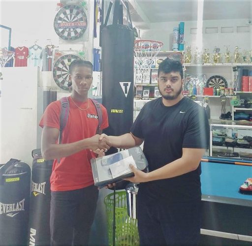 Shemar Halley (left) receives his sponsorship from Proprietor of West Indian Sports Complex, Javed Khan.