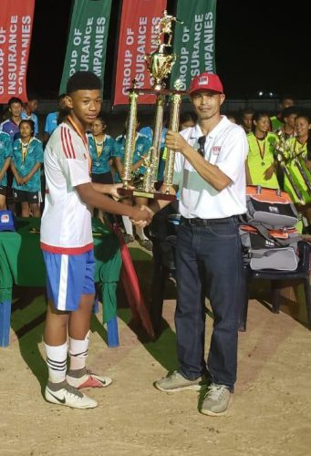 Ofancy Winter, captain of the Guyana Rush Saints Boys team receives the championship trophy from Chief Executive Officer of GTM Roger Yee.