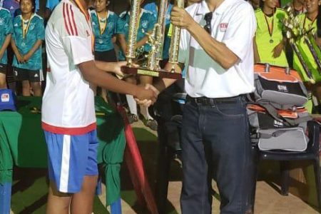 Ofancy Winter, captain of the Guyana Rush Saints Boys team receives the championship trophy from Chief Executive Officer of GTM Roger Yee.