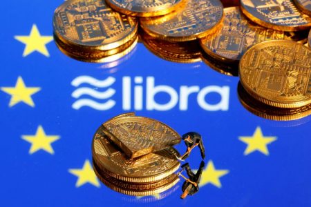A small toy figure is seen on representations of the virtual currency on a displayed European Union flag and the Facebook Libra logo in this illustration picture. (REUTERS/Dado Ruvic image) 