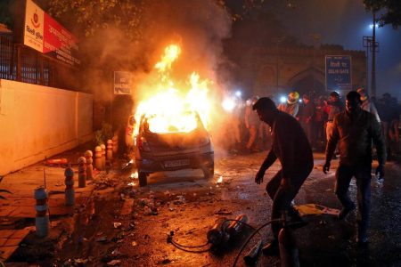 Men try to extinguish a burning car after demonstrators set it on fire during a protest against a new citizenship law, in New Delhi, India, December 20, 2019. REUTERS/Stringer
