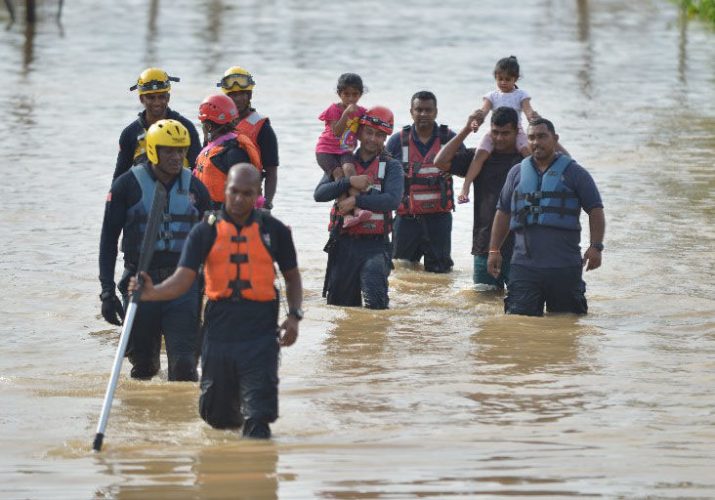 Trinidad Search and Rescue officers rescue a family from floodwaters yesterday. (Trinidad Express photo)