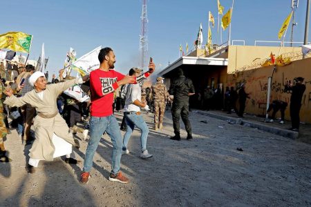 Protesters and militia fighters throw stones towards the U.S. Embassy during a protest to condemn air strikes on bases belonging to Hashd al-Shaabi (paramilitary forces), in Baghdad, Iraq December 31, 2019. REUTERS/Wissm al-Okili
