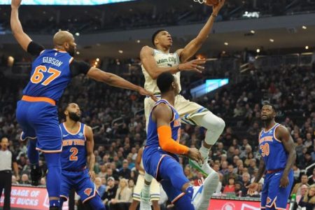 Milwaukee Bucks forward Giannis Antetokounmpo (34) lays up a shot against New York Knicks forward RJ Barrett (9) and forward Julius Randle (30) in the first quarter at Fiserv Forum. Mandatory Credit: Michael McLoone-USA TODAY Sports