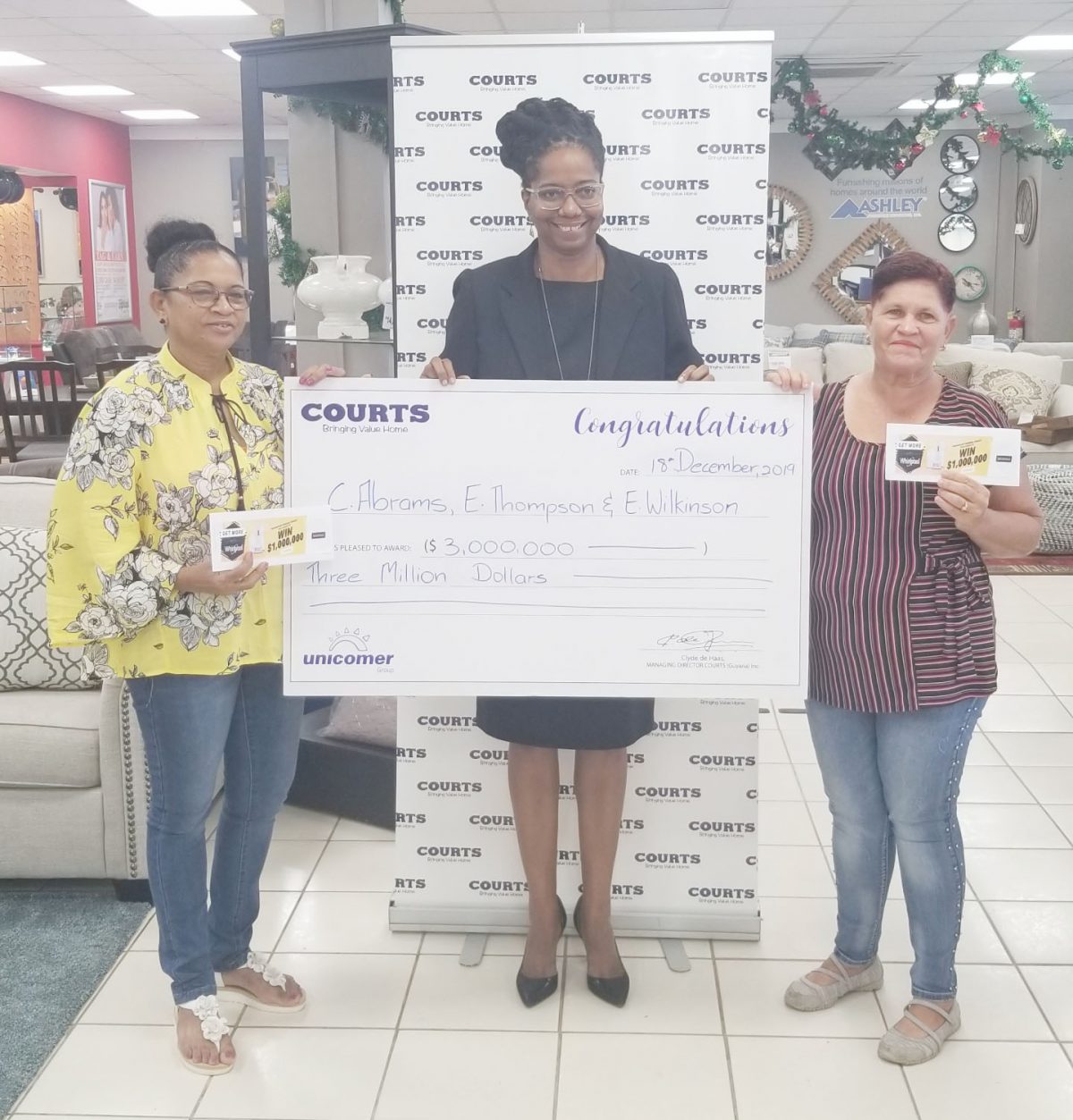 Winners Cecelia Abrams (left) and Elizabeth Wilkinson (right) receive their cheques from a representative of Courts, Helen Browman. 