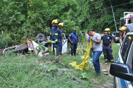 Police and fire officers at the scene where a truck transporting alcohol overturned on Lady Young Road, Port-of-Spain.
