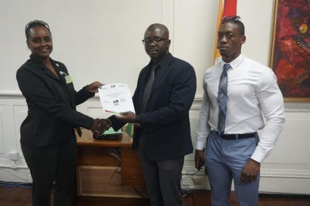 President of the Guyana Amateur Bodybuilding  and Fitness Federation, Keavon Bess presents a document to Assistant Director of Sport, Melissa Dow-Richardson in the presence of CAC gold medalist, Kerwin Clarke.
