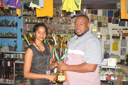Petra Organization Co-Director Troy Mendonca receiving the trophies from Trophy Stall staffer Anjali Persaud.
