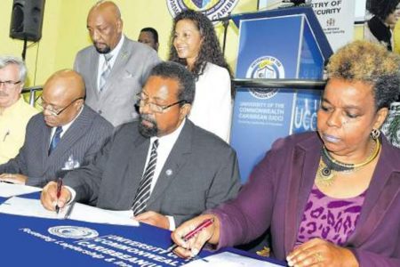 Permanent secretary in the Ministry of National Security Dianne McIntosh (seated, right); Professor Dennis Gayle (seated, second right), University of the Commonwealth Caribbean (UCC) president and executive chancellor; Department of Correctional Services Commissioner Lieutenant Colonel Gary Rowe (seated, centre); and director for Stand Up for Jamaica, Andre Schwab (seated, second left) sign the Memorandum of Understanding that will see four inmates and one correctional officer receiving scholarships to pursue the associate of science degree in business administration online at UCC. Also pictured are Geraldine Adams (seated, left), deputy executive chairman of UCC Group of Companies; Minister of State in the security ministry Rudyard Spencer (standing, left); and Professor Bernadette Warner, executive vice-president for academic affairs at UCC. (Photo: Michael Gordon)