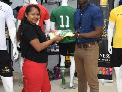 Guinness Brand Executive Lee Baptiste (right) receiving the symbolic tournament kits from Colours Boutique representative Marissa Williams following the official launch of the Guinness ‘Greatest of the Streets’ season. 