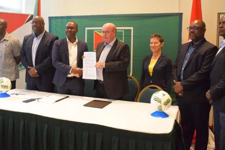 Flashback-DFA President Jesper Moller [center] and GFF President Wayne Force [3rd from left] displaying the signed development MoU following the official ceremony. Also in the photo from left to right are 1st Vice President Bruce Lovell, CONCACAF Senior Project Manager Howard McIntosh, UEFA Head of International Relations Eva Pasquier, 2nd Vice President Rawlston Adams and General Secretary Ian Alves