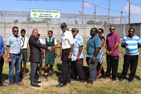 Minister of Social Cohesion Dr George Norton (left) shakes Alvin Johnson’s hand to finalize the handing over while members of the Guyana Cricket Board and Essequibo Cricket Board as well as school children look on.
