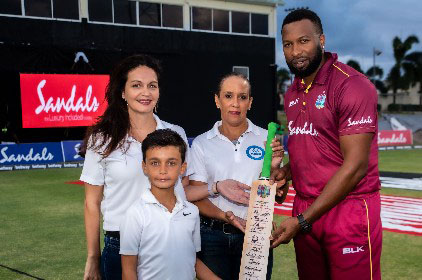 West Indies white-ball captain Kieron Pollard presents the autograph bat to PALS officials. (Photo courtesy CWI Media) 
