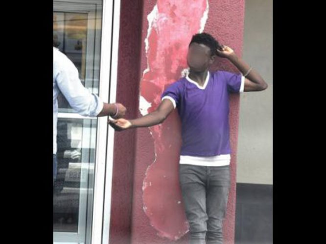 A teenage boy begs outside KFC in May Pen, Clarendon