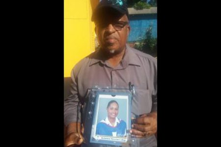 Neville Sinclair shows a photo of his daughter, Nevia, who was slain in Brinkley district, St Elizabeth, on Sunday night.