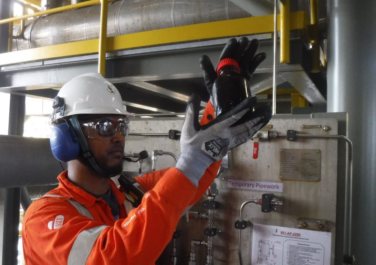 Shivnarine Outar collecting the first sample of oil for testing. (ExxonMobil photo)