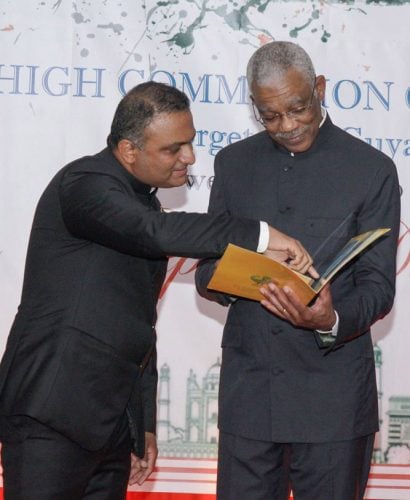 President David Granger (right) and Indian High Commissioner to Guyana Dr. KJ Srinivasa browse commemorative stamps issued by the Government of India on the occasion of the 550th birth anniversary of Guru Nanak Devji. The stamps were presented to President Granger on Sunday evening at the reception. (Ministry of the Presidency photo)