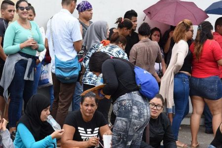 Venezuelan economic migrants wait on the pavement outside the Queen’s Park Oval in a line to be registered by the T&T authorities on June 12, 2019, as part of a process aimed at providing a work permit to all of the South American citizens living here.