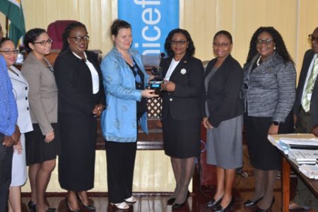 UNICEF country representative to Guyana and Suriname, Sylvie Fouet, presents Chancellor of the Judiciary, Justice Yonette Cummings-Edwards, (fourth from right) with a part of the Skype System that was set up at the Vigilance Magistrate’s Court. Looking on are Chief Justice Roxane George, Chief Magistrate Ann McLennan and others from the judiciary