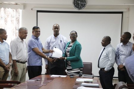 Minister of Education Dr Nicolette Henry (fifth from left) handing over  the contract to  CEO of BK International Inc, Brian Tiwarie.  (Ministry of Education photo)