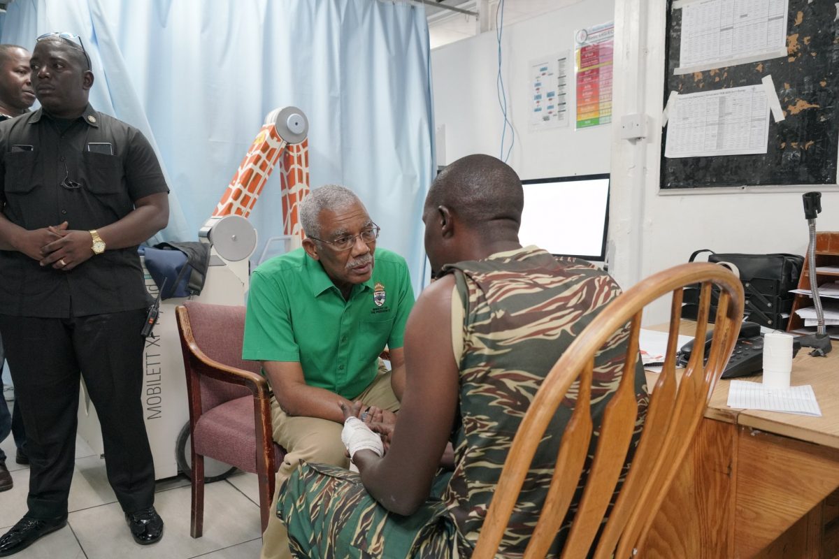 President David Granger interacts with an injured rank of the Guyana Defence Force. (Ministry of the Presidency photo)