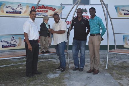 Winner Phillips, son of Alabama Trading Proprietor Wooed Phillips [left] officially hands over the team benches to Petra Organization Co-Director Troy Mendonca in the presence of Lawrence ‘Sparrow’ Griffith [2nd right] and Mark Alleyne [right] .
