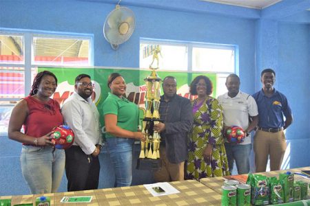Petra Organization Co-Director Troy Mendonca [center] receives the first place trophy from as Milo Brand Ambassador Shellona David in the presence of several members of the launch party of the Milo Secondary School Football Tournament.